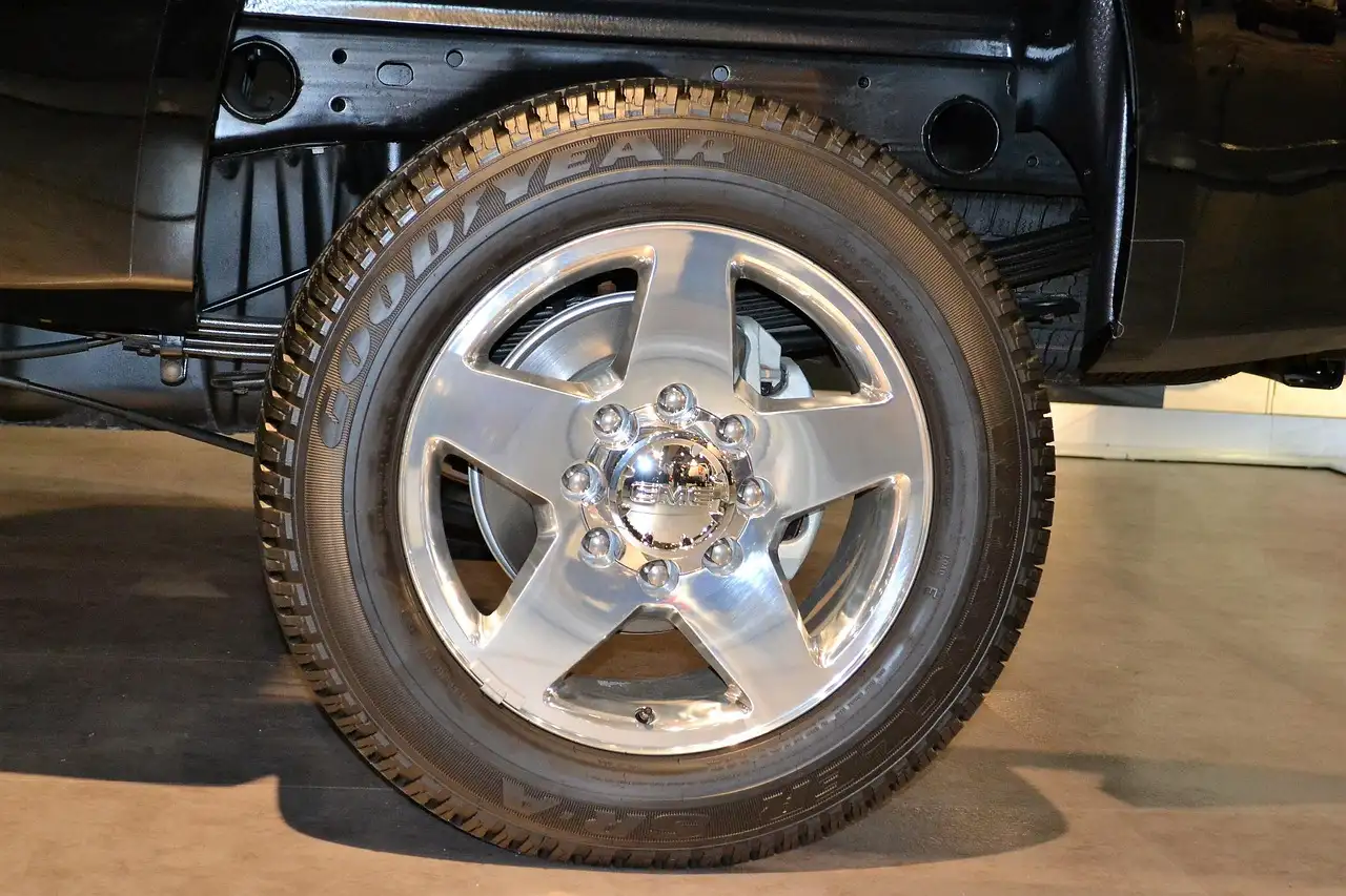 Mechanic inspecting a rear axle seal leak near the wheel hub on a sedan
