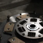 Mechanic testing clutch slip in a manual car with brake and clutch pedal visible