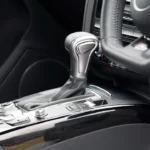 Driver beside a sedan with the hood open, concerned about an automatic transmission issue
