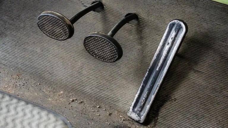 Mechanic inspecting a clutch pedal stuck on the floor in a car footwell