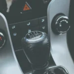 Mechanic inspecting a manual transmission in a cold garage beside a sedan