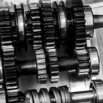Mechanic inspecting a manual transmission car's shifter and clutch pedal area in a bright repair bay