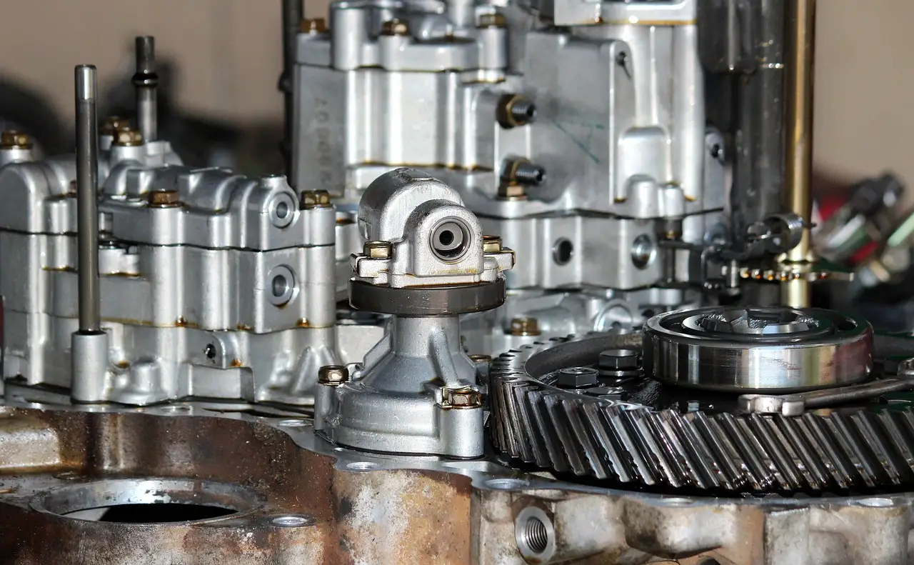 Mechanic inspecting a sedan on a lift while diagnosing transmission noise during acceleration