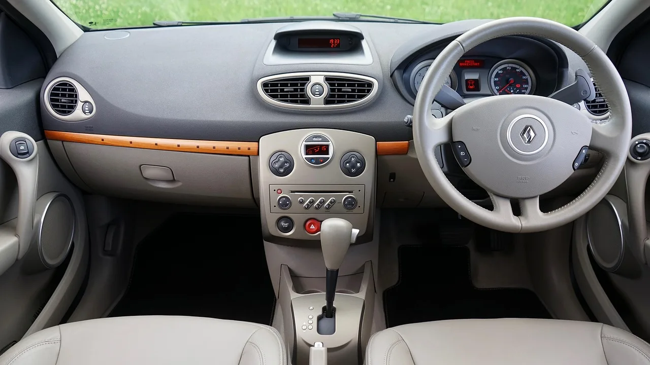 Mechanic checking a sedan's gear selector beside the driver door in natural light.